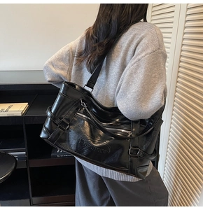 Detail of the large black tote bag featuring textured PU leather and decorative zipper accents