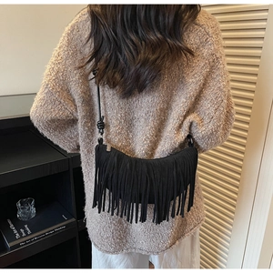 Detail shot of black suede crescent bag with long fringe tassels and knotted shoulder strap