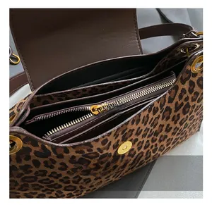 Internal view of leopard print bag showing multi-compartments and golden zipper details