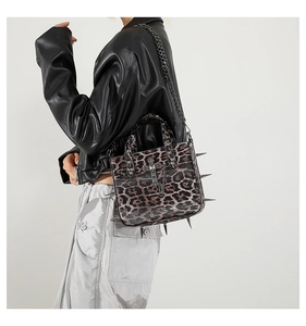 Detail view of leopard print tote with metal spikes and gothic cross pendant detail