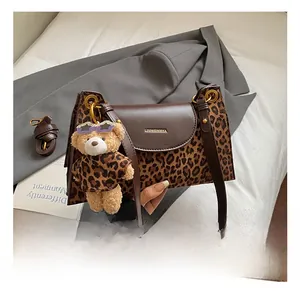 Detail of leopard print shoulder bag with gold ring buckle and cute bear plush charm
