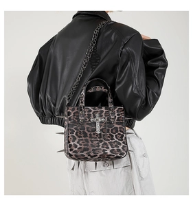 Detail of leopard print tote bag with metal cross, punk rivets and thick chain strap