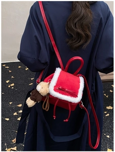 Mini red velvet backpack with white faux fur trim and cute bear charm in outdoor setting