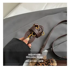 Detail showing adjustable dark brown leather shoulder strap with golden metal hardware buckle