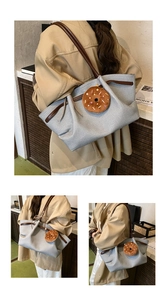 Detail of grey canvas tote bag with brown leather handles and plush donut charm