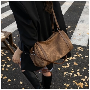 Outdoor shot of a vintage brown Boston bag with adjustable leather straps on a street
