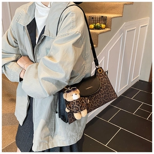Close-up of leopard print shoulder bag with black leather flap and cute bear pendant
