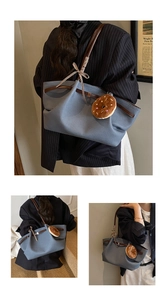 Detail of blue canvas tote bag with brown handles and a plush donut charm accessory