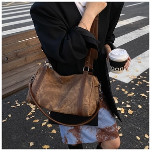 Close-up of deep brown vintage crossbody bag with textured fabric in a street setting