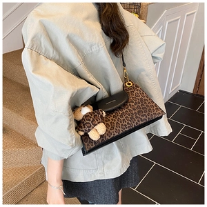 Detail of leopard print handbag with black flap, golden hardware and cute teddy bear charm