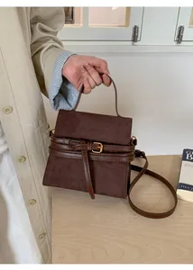Detalle de bolso de ante marrón vintage con hebilla de cuero y correa de bandolera
