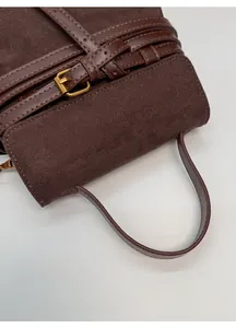 Detalle de bolso vintage de ante marrón con correa de cuero y hebilla dorada