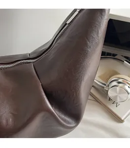 Detailed close-up of dark brown soft PU leather texture and silver zipper on dumpling bag