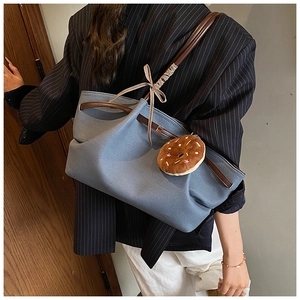 Detail of light blue canvas tote with brown leather straps and plaid bow decoration
