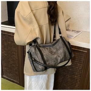 Detailed side view of the gray cylinder Boston bag with premium leather straps on a model