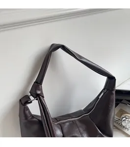 Detail of soft brown PU leather hobo bag featuring a knotted shoulder strap and metal ring