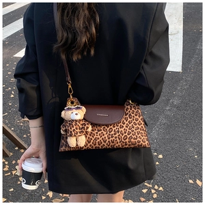 Detail of leopard print crossbody bag with brown leather flap and cute bear pendant