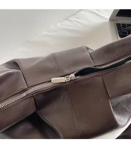 Detailed macro view of high-quality smooth zipper puller on a dark brown leather bag