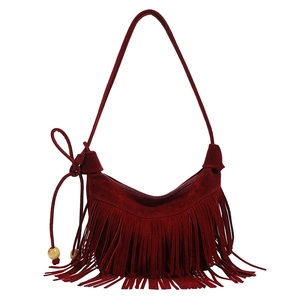 Detailed close-up of dark red suede fringe bag with bohemian wooden beads and smooth texture
