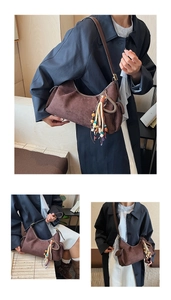Détail du sac hobo en daim marron rétro avec pompon coloré bohème et poche latérale pratique