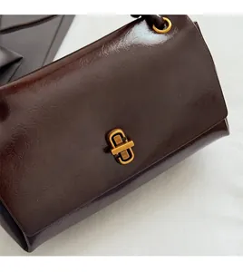 Detailed close-up of dark brown oil wax leather bag with a golden metal rotary lock