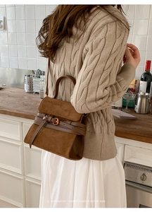 Detalle de bolso retro de ante marrón con adornos de cuero y hebilla metálica de alta calidad