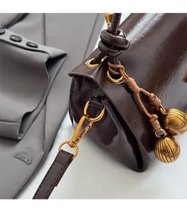 Close-up of vintage gold hardware and glossy dark brown leather on the crossbody bag