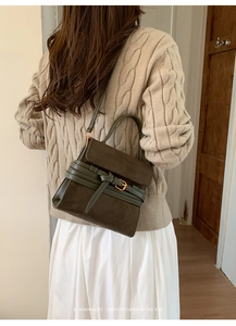Detalle del bolso retro verde oscuro con hebilla metálica y textura de acabado mate