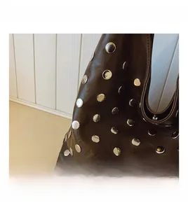 Close-up of silver metal rivets on dark brown leather of the autumn tote bag