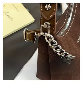 Détail du sac bandoulière en daim marron foncé avec chaîne argentée et gaufrage fashion