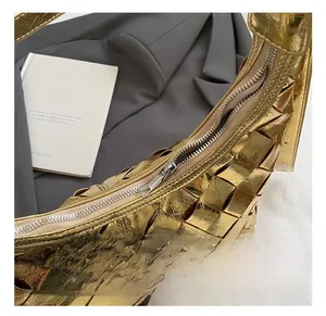Nahaufnahme der goldenen Flechtstruktur und des silbernen Reißverschlusses der Tasche