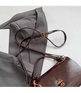 Detail of dark brown leather handbag with adjustable strap and metal twist lock