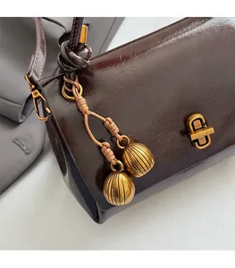 Close-up of vintage gold square twist lock and woven tassel on dark brown leather handbag