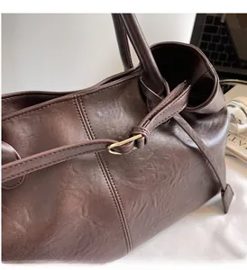 Gros plan d'un sac cabas en cuir marron foncé avec boucle dorée et sangle ajustable