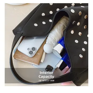Internal capacity of black rivet tote bag showing umbrella, phone and notebook