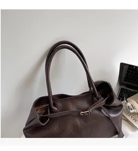 Gros plan du sac cabas marron foncé avec texture litchi et finitions dorées