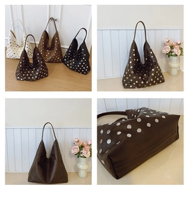 Macro detail of high-capacity leather tote bags featuring silver rivet stud decorations