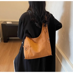 Detail of caramel suede hobo bag featuring decorative woven ties and metal ring accents