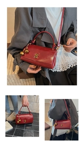 Detail of red vintage rectangular crossbody bag with gold bell accents and metal twist lock