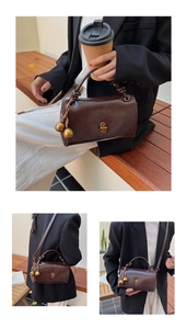 Detail of vintage brown leather bag with metallic clasp and decorative ball charm