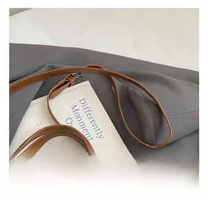 Detail of adjustable leather strap and hardware buckle on brown matte suede tote bag