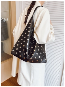 Detail of black leather hobo bag with silver studs worn as a stylish shoulder bag