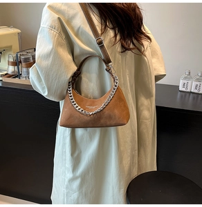 Détail du sac bandoulière en daim caramel avec chaîne argentée et logo en cuir chic