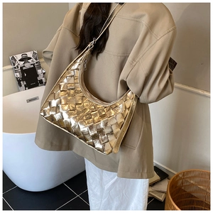Detailaufnahme einer goldenen geflochtenen Hobo-Tasche über der Schulter in Interieur