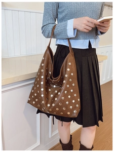 Detailed view of a brown leather tote bag featuring stylish silver metal rivets and studs
