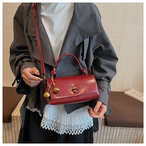 Detail of burgundy glossy leather bag with gold clasp and decorative spheres