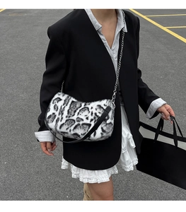 Vue de rue extérieure d'un sac à bandoulière en peluche à motif vache avec chaîne argent