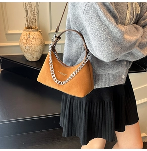Détail du sac en daim mat marron montrant la chaîne argentée et la texture du cuir