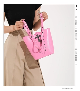 Pink punk bucket bag featuring metallic rivets and a dark cross charm detail