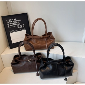 Détails de trois grands sacs cabas en cuir marron, café et noir sur un présentoir blanc